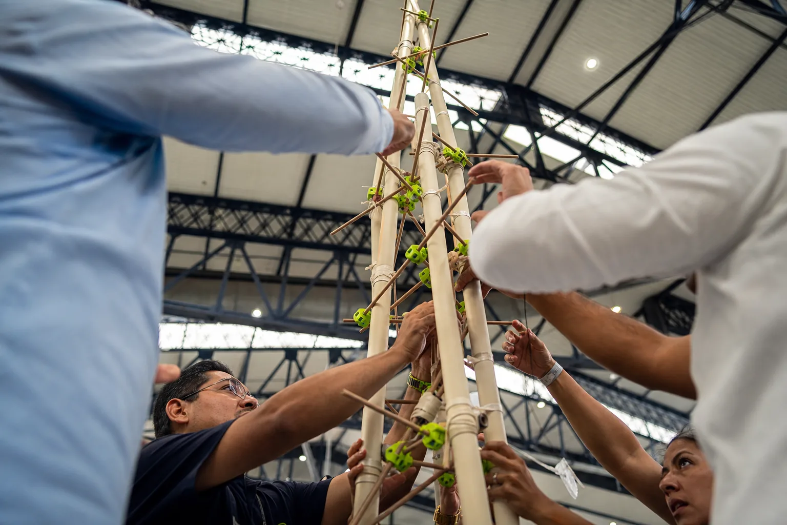 Equipo adulto estabilizando una torre alta construida con tubos y varillas